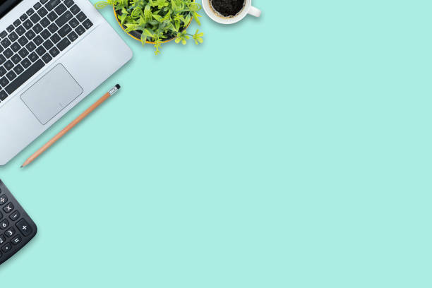istock Stylish office table desk. Workspace with laptop, calculator, blank notebook and pencils on pastel green background. 1407461615