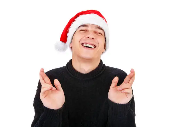 Young Man in Santa Hat crossing his Fingers Isolated on the White Background