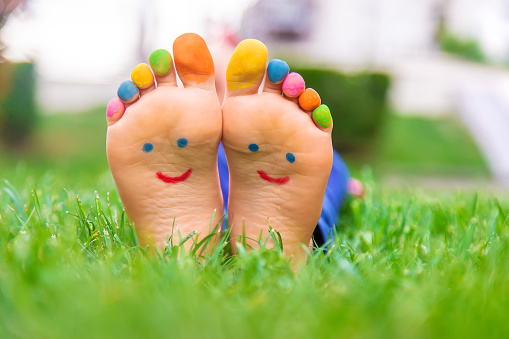 Feet of a child on the grass with a painted smile. Selection focus. Kid.