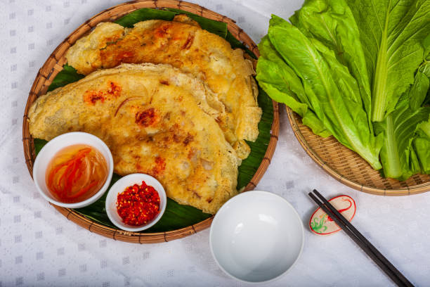 Vietnamese Banh Xeo crepes filled with pork or chicken may also, shrimp, onions and bean sprouts, and hot sauce placed near the plate on the table stock photo