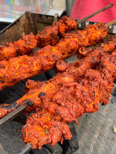 istock Full frame image of uncooked chicken kebabs, marinated raw chicken breast pieces on metal skewers, lying in rows over hot charcoal embers, elevated view, focus on foreground 1407466815
