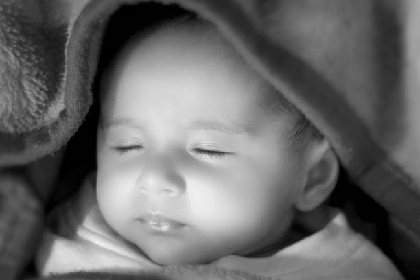 Baby hands closeup. Mom embrace infant child enjoying together at home. A young mother holds a newborn baby son. Loving mom on maternity leave. Mother's day concept. Black and white photo.
