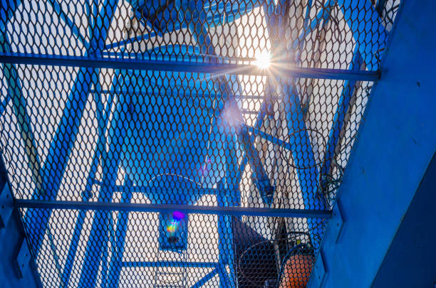 istock Metal blue industrial mesh. The sun's rays shine through the metal structure. 1407470426