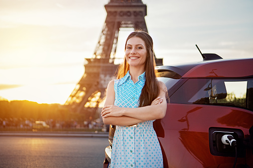 Portrait of woman charging her electric car in Paris