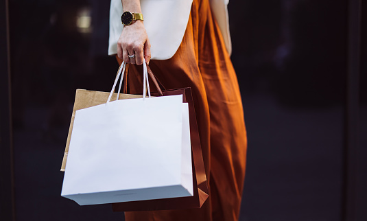 An anonymous businesswoman carrying paper bags while walking at the city street.