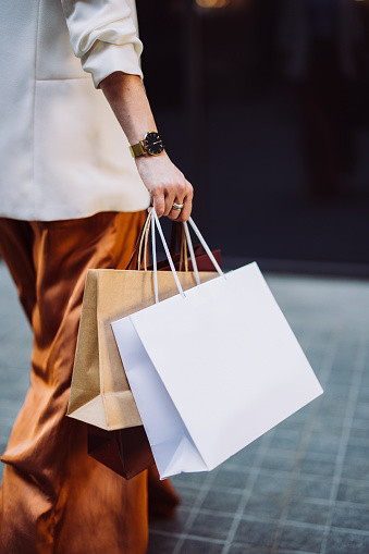 An anonymous businesswoman carrying paper bags while walking at the city street.