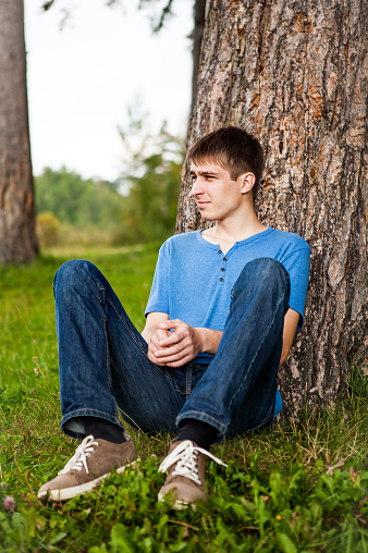 Young Man sit under the Tree in the Park