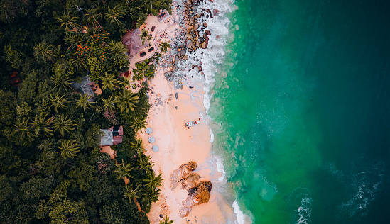 Drone point of view on a beautiful secluded, empty beach with turquoise water in a small bay.