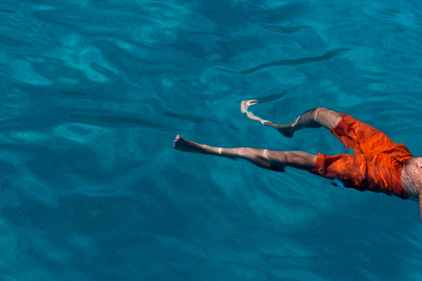 istock Unrecognizable man floating in the blue sea 1407477665