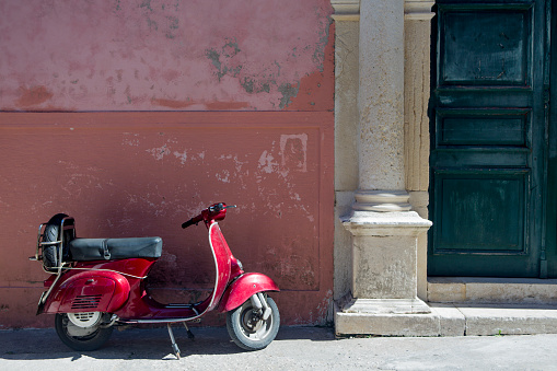 Vintage red scooter in front of a house  in Paxos, Greece.