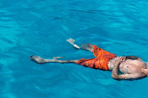 istock Unrecognizable man relaxing and floating in the blue sea 1407477818