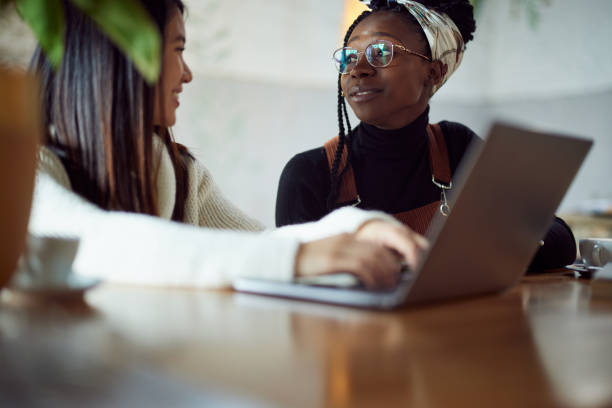 istock Two multicultural female students sitting in cafeteria and study for exam. 1407484775