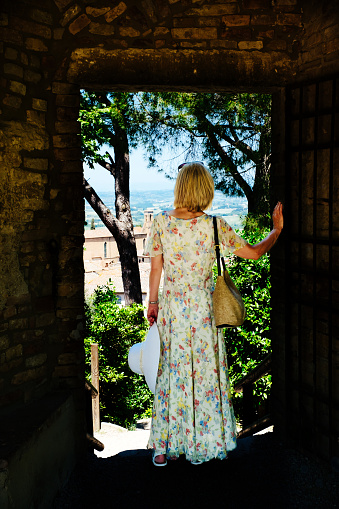 Mature woman passing through a doorway in Tuscany, Italy.