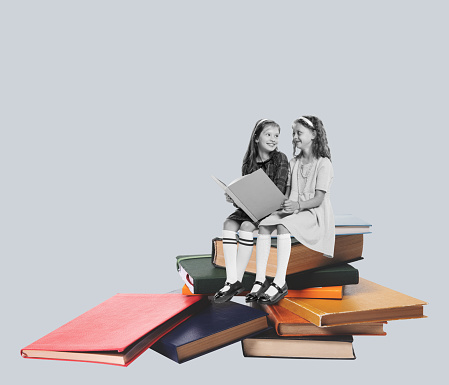 Contemporary art collage. Two beautiful girls, children sitting on books, reading isolated on grey background. Concept of retro design, creativity, imagination, education, inspiration, artwork and ad