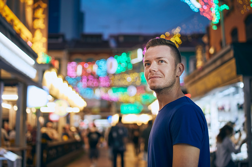 Portrait of man on evening illuminated street market. Tourist in Chinetown in Singapore.