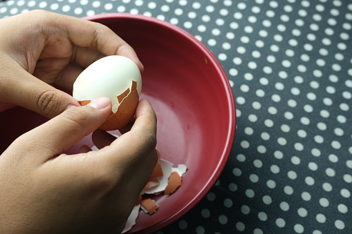 Hands peeling off boiled egg