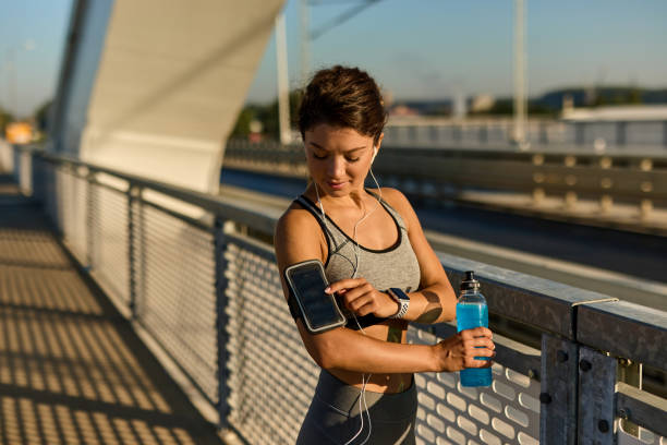 istock Female runner adjusting music on mobile phone before jogging 1407494778