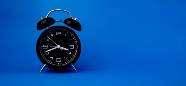 istock Black alarm clock on blue background, importance of time concept and time work. 1407495169