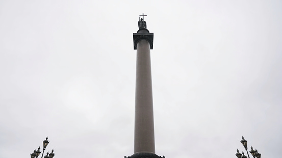 The Alexander Column in the middle of the Palace square in St. Petersburg, Russia. Bottom view of a giant granite column on cloudy sky background.