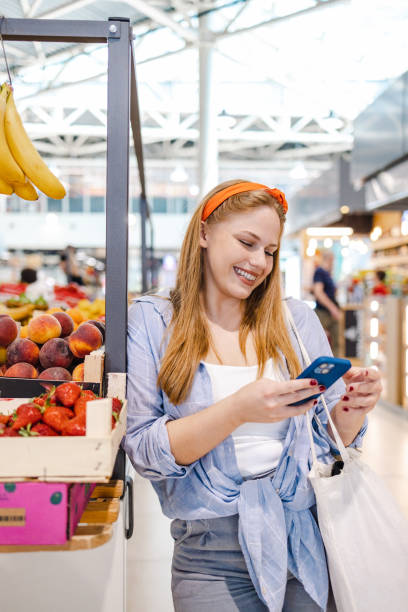 istock Young woman using mobile phone on a farmer's market 1407496713
