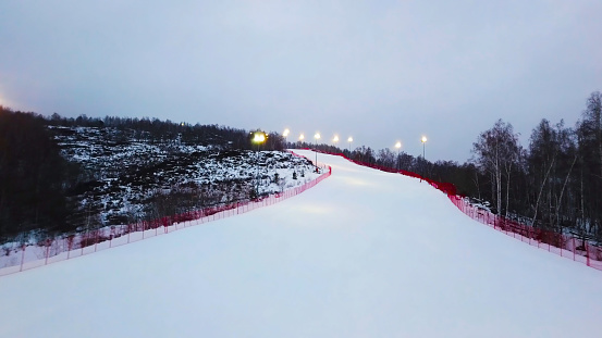 Top view of empty ski slope in winter. Stock footage. Beautiful deserted ski track near forest on winter evening day. Ski winter vacation.
