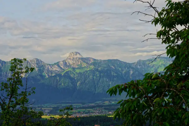 Panoramic view of the sunny Stockhorn mountan with some clouds above and framed by green leaves