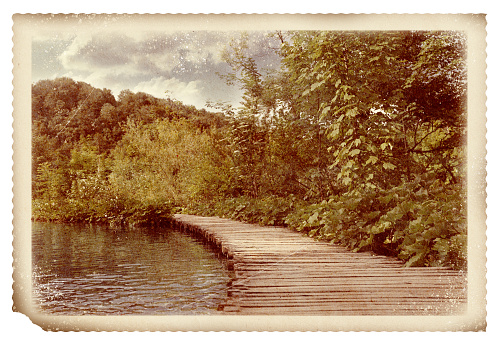 Old paper photo. Wooden bridge over river and beautiful view of forest