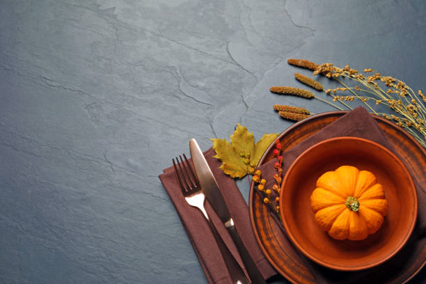 istock Autumn table setting with floral decor and pumpkin on dark grey background, flat lay. Space for text 1407505644