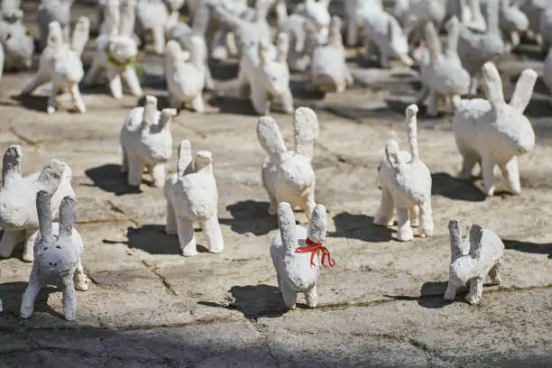 Photo of White rabbit statues made of plaster at outdoor art exhibition, funny white hares on street