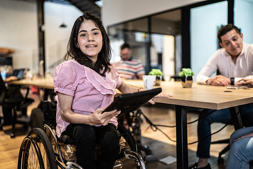 Portrait of disabled young woman using digital tablet at work