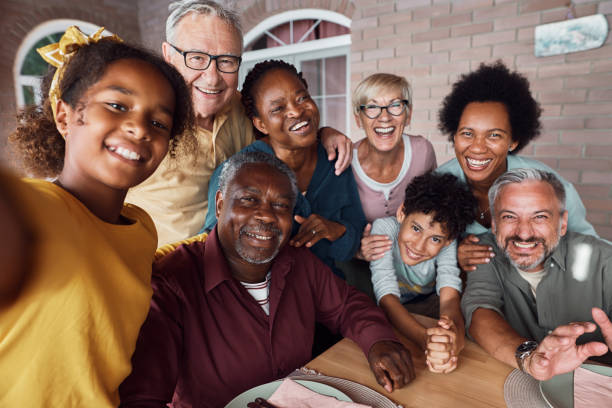 Happy multiracial extended family having fun while taking selfie on a patio. Cheerful multiethnic extended family taking selfie and having fun together while gathering on patio. multiracial person stock pictures, royalty-free photos & images