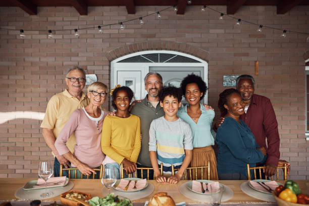 istock Happy multiracial extended family gathering at dining table on patio and looking at camera. 1407511384