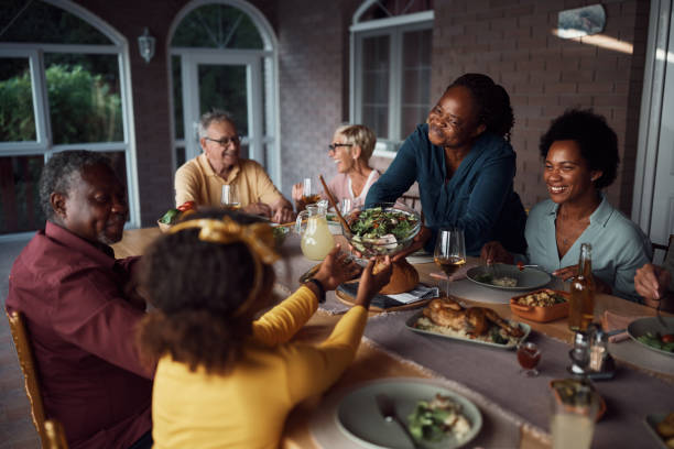 istock Happy multi-ethnic extended family enjoying while gathering for meal at dining table on a patio. 1407512029