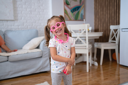 Portrait of cute Caucasian toddler girl, dressed as an doctor, wearing pink eyeglasses and pink stethoscope