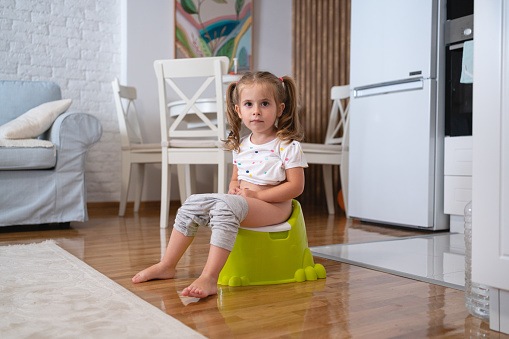 Portrait of toddler girl on a potty at the living room