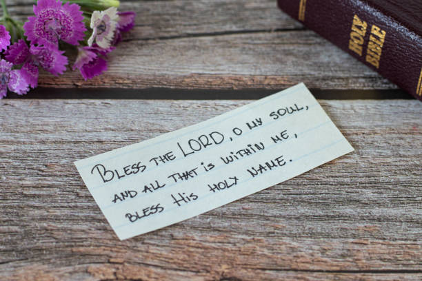 handwritten note with christian text verse and a closed holy bible book on a wooden table with flower - psalms imagens e fotografias de stock