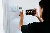 Close Up Of Woman Holding Smart Energy Meter In Living room Measuring Energy Efficiency