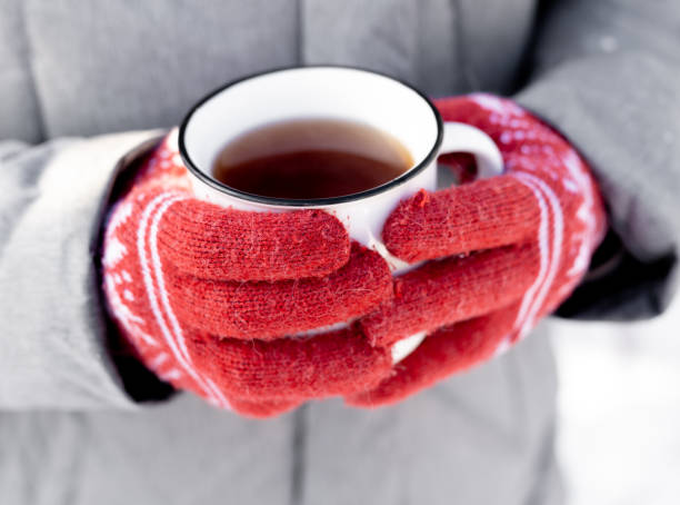 Hands in gloves holding cup Hands wearing red knitted gloves holding mug with hot beverage cocoa in winter snow time outdoors. Person with warm tea coffee in cup Knitted Gloves stock pictures, royalty-free photos & images