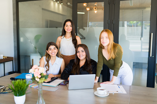 Portrait of an attractive diverse group of women smiling and working on a project as a team at the office