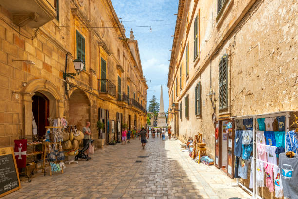 A picturesque street of shops and cafes near the Santa Maria Cathedral in the historic center of Ciutadella de Menorca, on the island of Menorca, Spain. A picturesque street of shops and cafes near the Santa Maria Cathedral in the historic center of Ciutadella de Menorca, on the island of Menorca, Spain. minorca stock pictures, royalty-free photos & images