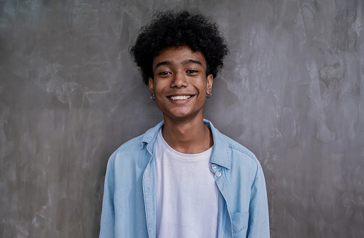 Portrait of young smile handsome black African American man on gray wall background. Happy afro guy online influencer blogger. Education model teenager boy lifestyle.