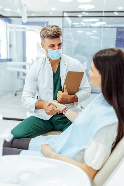freundlicher zahnarzt, der sich mit einer patientin unterhält - dentist dentist office patient discussion stock-fotos und bilder