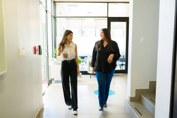 istock Smiling female co-workers talking and walking at the office 1407524119