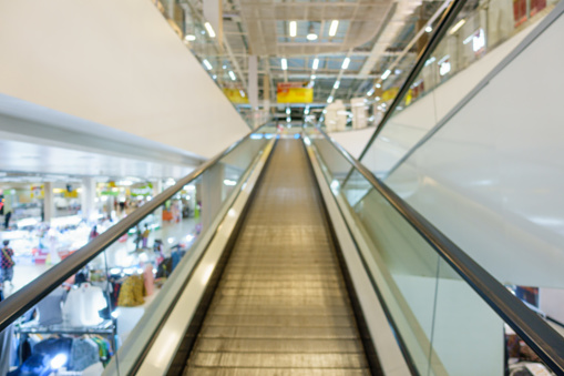 Blurred picture photo of an escalator or moving staircase in a supermarket or shopping mall, a type of vertical transportation which carries or conveys people between floors of a public building.