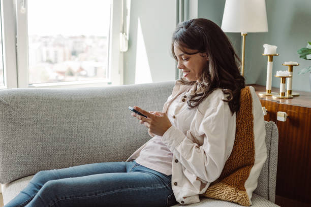 istock Young woman using mobile phone at home. Scrolling through social media 1407527435
