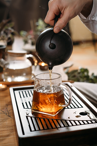 Traditional Chinese tea ceremony Gun Fu Cha and pouring oolong from a teapot with vapor on a dark background
