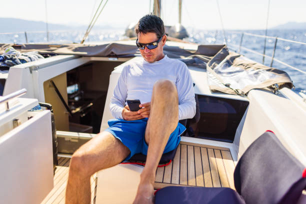 istock Businessman with smart phone on sailboat 1407530880