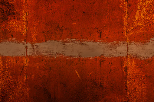 Dark orange-brown texture of rusty metal in grunge style. Rusty corrosion and oxidized background with a strip of paint.