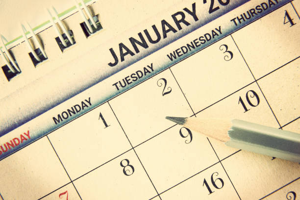 istock Calendar planner / timetable or schedule arrangement concept : Top view of a silver pencil on a flipped paper / desk calendar. A calendar is a system of organizing days for administrative purposes. 1407532178