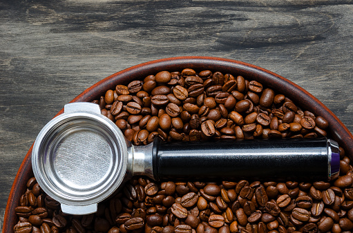 The coffee horn lies on coffee beans and on a ceramic plate. On a black background.